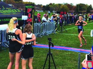 Junior Mimi Reimers and sophomore Sophie Carrier watch teammate sophomore Alexa Jankowsky cross the finish.