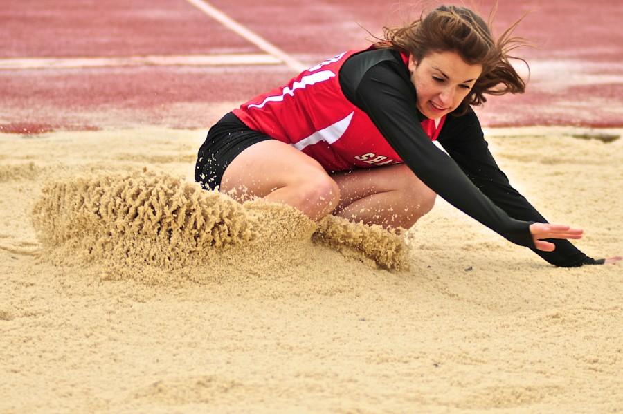 Junior Hannah Heverling lands into the sand after a long jump attempt April 30, 2014.