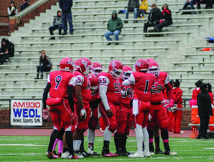 Junior quarterback Craig Robinson calls a play in the offensive huddle in front of a sparse crowd during a Saturday afternoon home game. 
