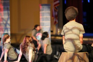 Before the show, freshmen sit upon a stage created to look like a broken down building, watching old-school horror movies.