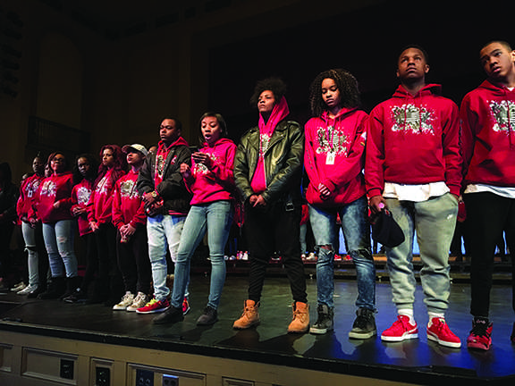 Senior Mekkah Husamadeen prompts audience to put their hoods up for a 10-second moment of silence to honor Trayvon Martin during the Sankofa preview assembly.