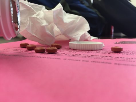Ibuprofen and tissues lay on top of a sick students essay assignment. 