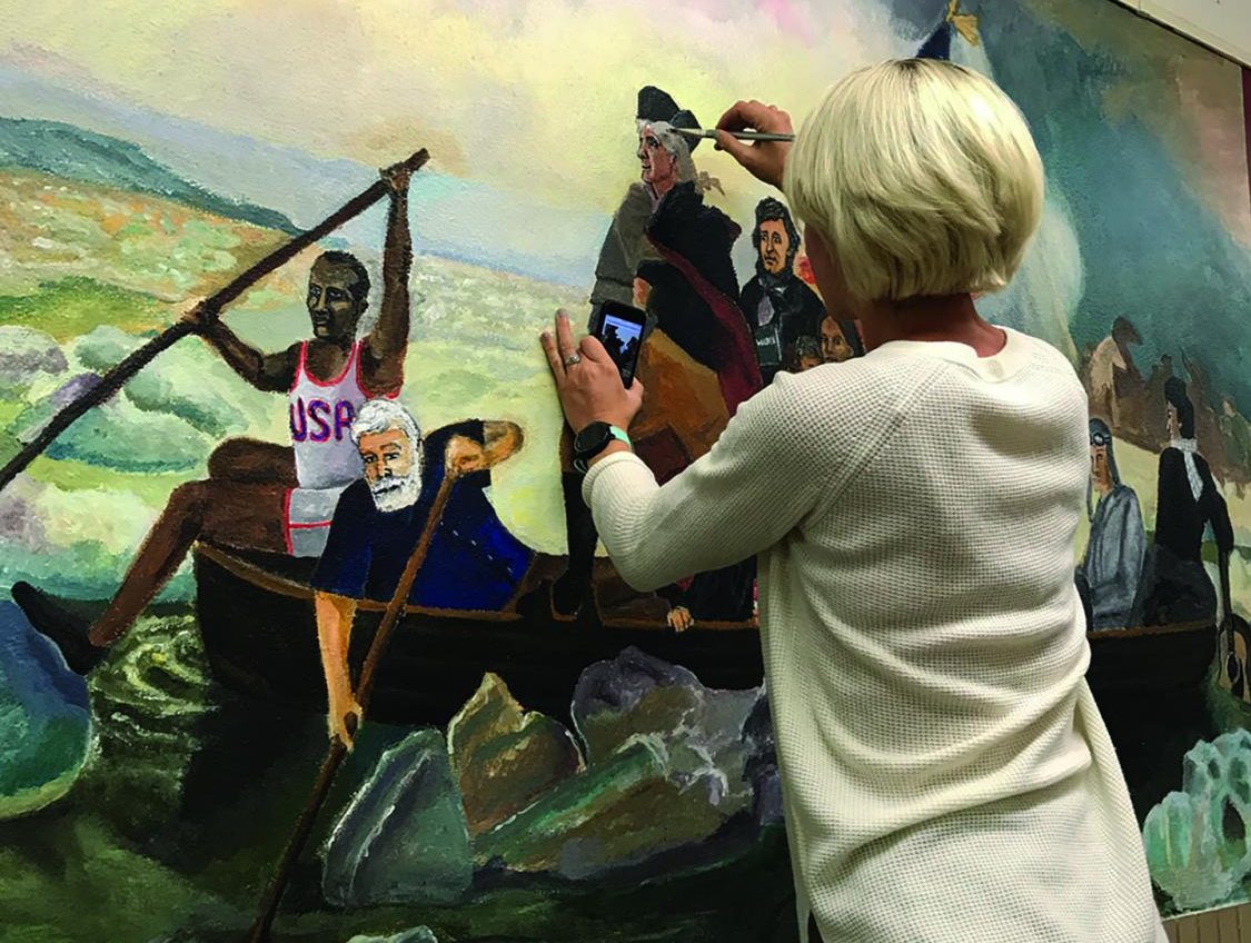 Art teacher Meryl Haring paints over the face of Timothy Mitchell on a mural portraying him as George Washington Oct. 17.
