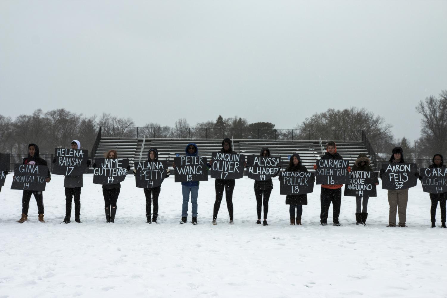 Students line up on the turf at Russell H. Rupp Stadium, each holding a poster naming a victim of the Parkland school shooting.