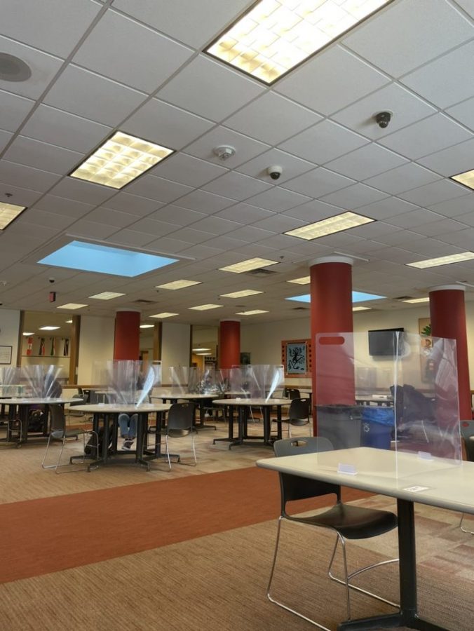 Cafeteria tables, equipped with two flexible plastic screens each, await students for lunch on the first day of hybrid instruction, Jan. 19, 2021.
