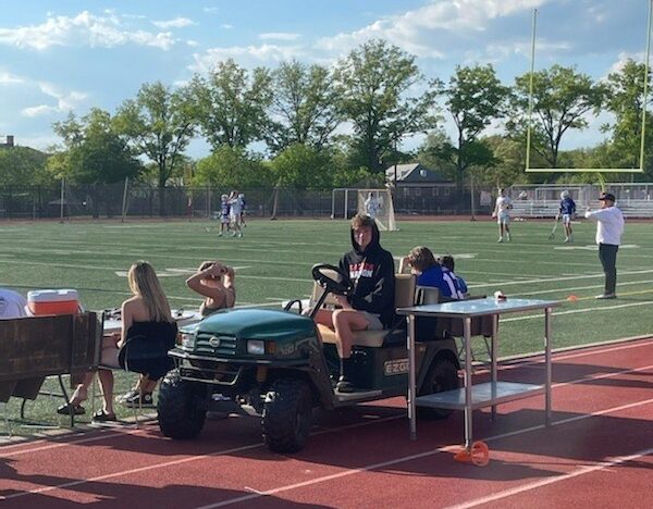 Student Intern Henry Sheperd assists with a Girls' Lacrosse game on the sideline