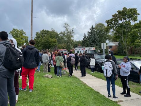 Students stand outside the high school with fire trucks visible in the background.