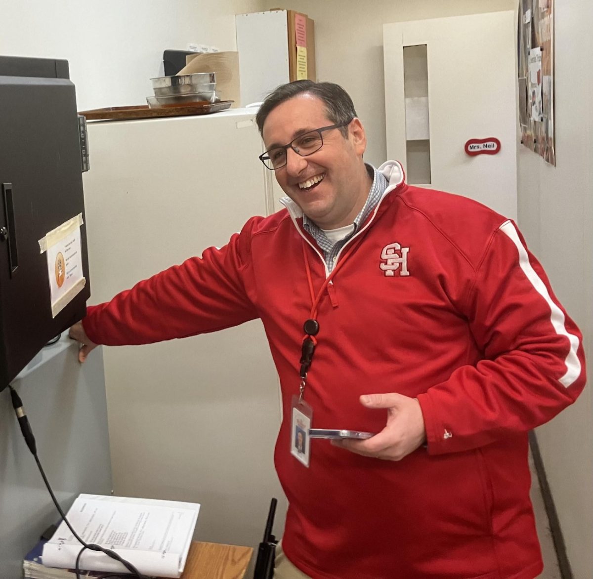 Principal Eric Juli at the main office P.A. station Nov. 22, his last day at work with students. Juli delivered daily Words of Wisdom messages and deejayed music during passing periods from this spot throughout his tenure, which began in August 2019.  Today, Juli shared a quote from John Wesley, an English theologian of the 18th century: “We do all the good we can/By any means we can/In all the ways we can/In all the places we can/At all the times we can/To all the people we can/As long as we ever can.”

