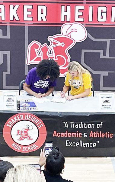 Sporting their future alma maters' colors, B'Lise Bradley and Lizzy Favret sign their letters of intent Nov. 13 in the North Gym during the Athletic Department winter media day ceremony. 