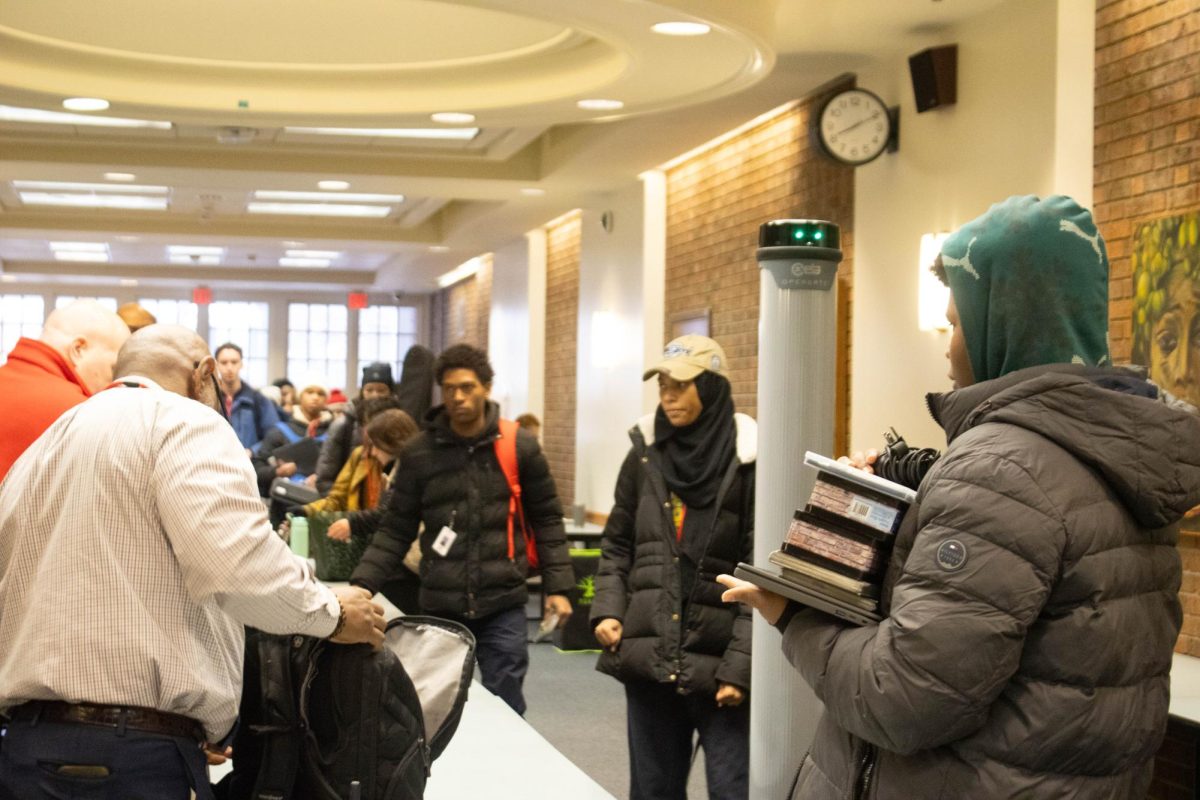 Aden Sowell, a sophomore, holds his belongings while his backpack is inspected in the egress Jan. 23. Students were instructed to remove from backpacks three-ring binders, Chromebooks, spiral notebooks phones, airPods and headphones before passing through detection. If the system alerted, students' bags were inspected manually. 