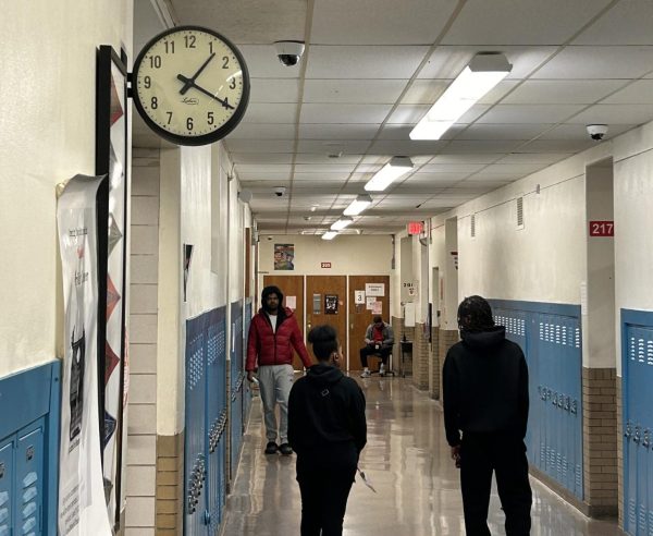 Students walk past a two-sided analog clock in the second floor main hallway.