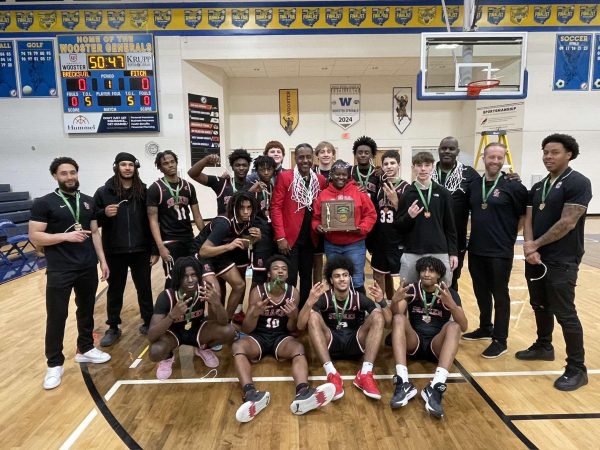 The men's basketball team poses with the district championship trophy following their 72-67 victory against Massillon Washington on March 2. It is the team's first district championship since 2019-20.