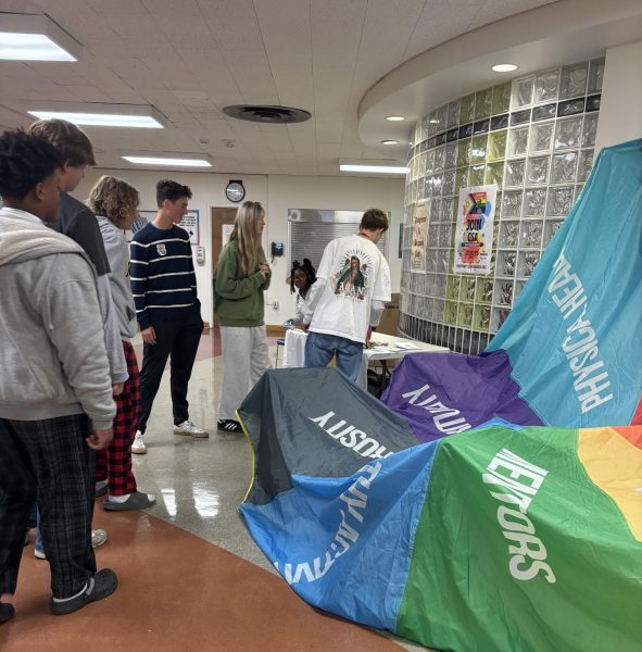 Students visit the Sources of Strength information table in the upper cafeteria Oct. 22. The parachute represents mental health, family support, positive friends, mentors, healthy activities, generosity, spirituality and physical health. 