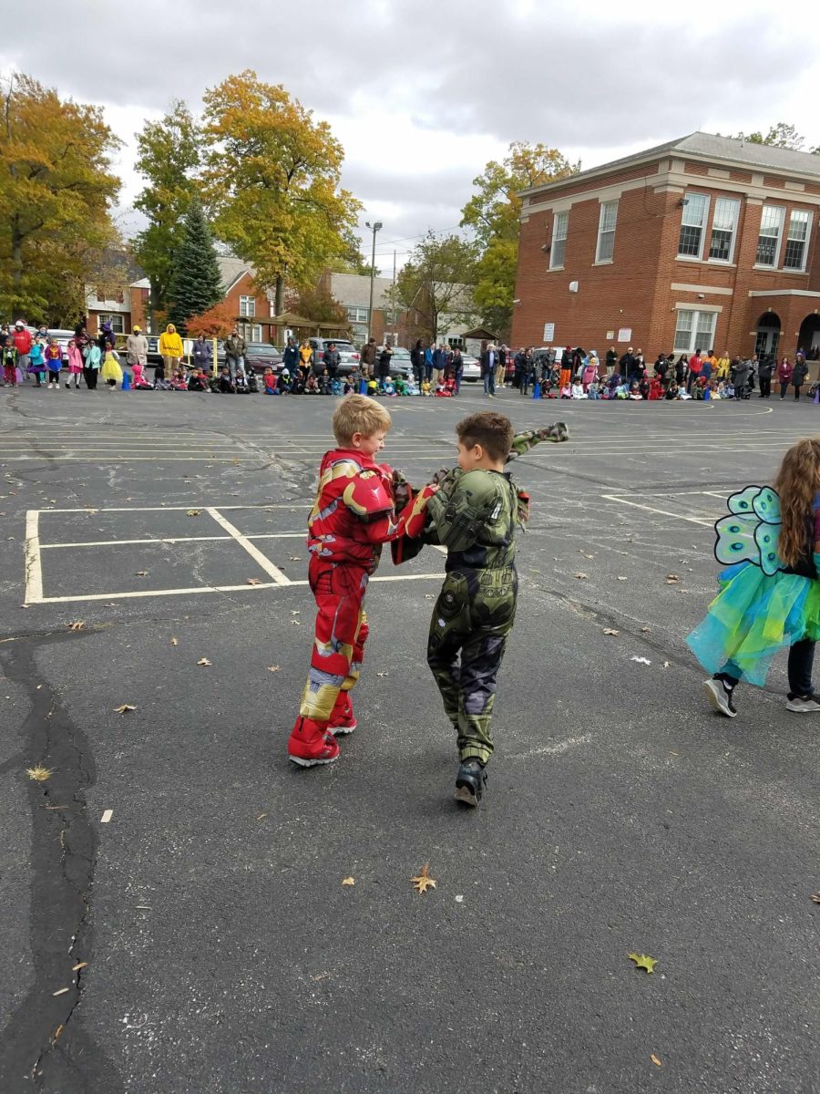 Costumed students do battle in the parking lot as classmates gather for Halloween fun. The district’s school observations of the holiday ended in 2021, a decision in line with national trends. Schools throughout the country have elminated Halloween and Valentine’s Day celebrations, which violate some religious beliefs, Concern about excluding students who cannot afford to participate also informs such decisions.
