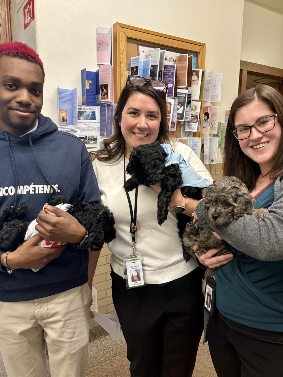 Freshman Ian James, Instructional Coach Dr. Elizabeth Mangan, and IB Middle Years Programme Coordinator Kailey Uhl, pose with puppies outside room 221 on March 18. The puppies, brought by New Era Cleveland chairman Antoine Tolbert, provide therapy to students as part of the organization's outreach efforts. "We come one to two days a week to support mentorship, conflict mediation and provide a safe space for students," Tolbert said. 