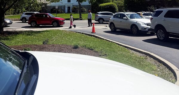 Cars, students, security and a traffic cone populate the high school's main entrance parking lot April 30. 